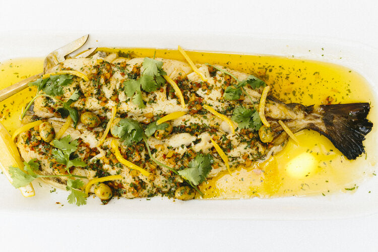 Picture of roasted fish covered in zest and chopped herbs and spices